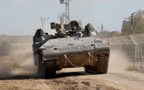 A picture taken from a position in southern Israel along the border with the Gaza Strip shows a APC (armoured personal carrier) rolling along the border on December 29, 2023, amid continuing battles between Israel and the militant group Hamas. (Photo by JACK GUEZ / AFP)