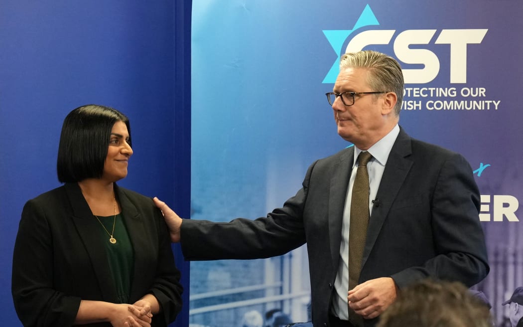 Britain's Home Secretary Shabana Mahmood (L) and Britain's Prime Minister Keir Starmer react as they speak to members of the Jewish community at the Community Security Trust (CST) in north west London on October 16, 2025, where they discussed the Government's response to the attack at the Heaton Park synagogue in Manchester. (Photo by CARLOS JASSO / POOL / AFP)