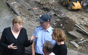 German Chancellor Angela Merkel, left, and Malu Dreyer, right, Prime Minister of Rhineland-Palatinate, stand on a bridge overlooking the flood-ravaged village of Schuld near Bad Neuenahr-Ahrweiler.