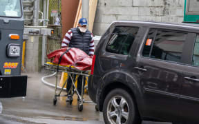 A funeral home employee loads a body to be transported a refrigerated trailer in New York City.