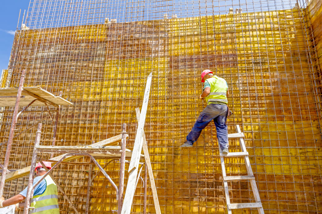 Construction worker is binding rebar for tall reinforced concrete construction.