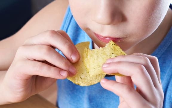 Little boy eating potato chips.