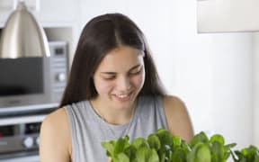 Georgia Lala standing beside one of her aquaponics tanks
