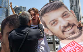 A member of the Israeli security forces scuffles with a protester holding a cutout of a hostage, during an anti-government protest in Tel Aviv on 17 August 2025 demanding a deal to release Israelis detained in the Gaza Strip by Hamas militants.