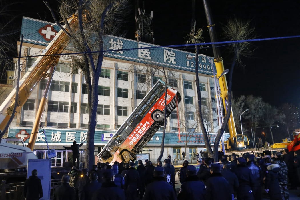 Chinese rescuers watching as a bus is lifted out after a road collapse in Xining in China's northwestern Qinghai province on 13 January, 2020.