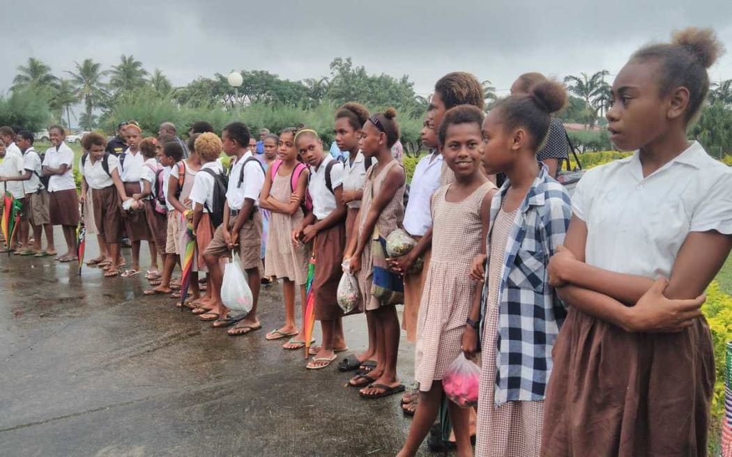 Children are lining the route from the Vanuatu parliament to the airport as the funeral procession takes the President Baldwin Lonsdale back to his home.