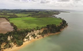 Drone shot of Kaipara Harbour with farm land of South Head in foreground, New Zealand