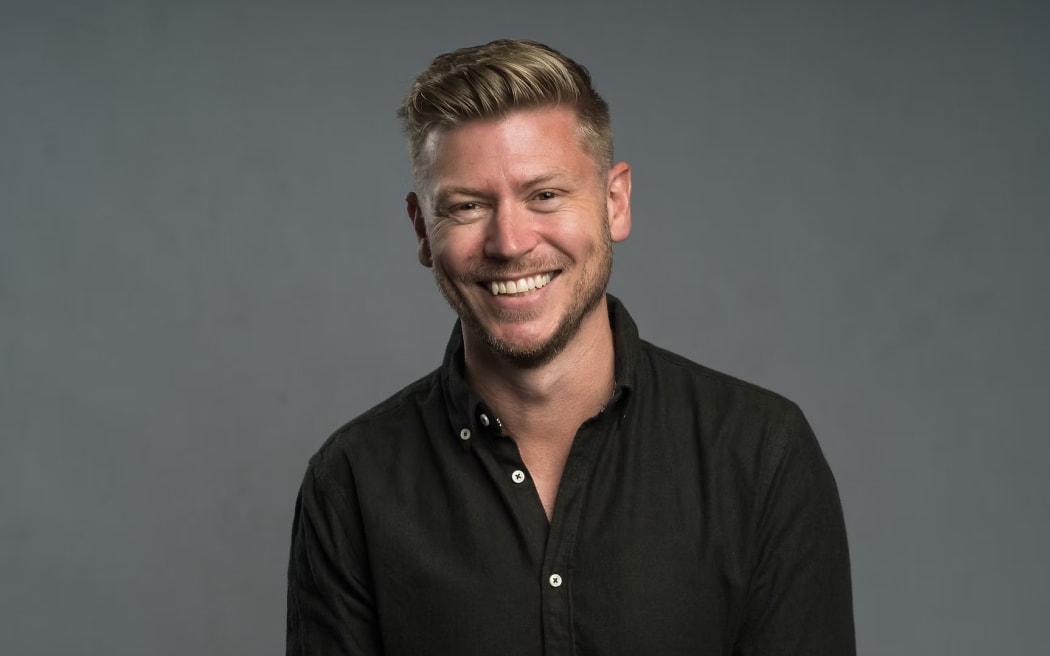 Matt Gibb is a smiling blonde haired man in a black shirt.