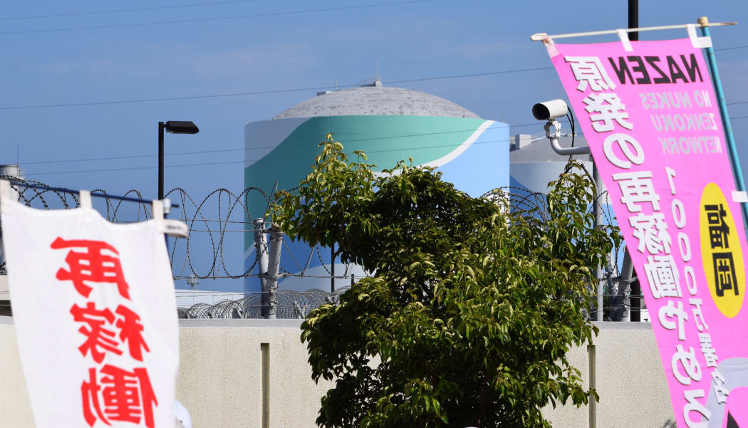 A nuclear reactor building can be seen through banners protesting the restarting of the Kyushu Electric Power plant in Sendai.