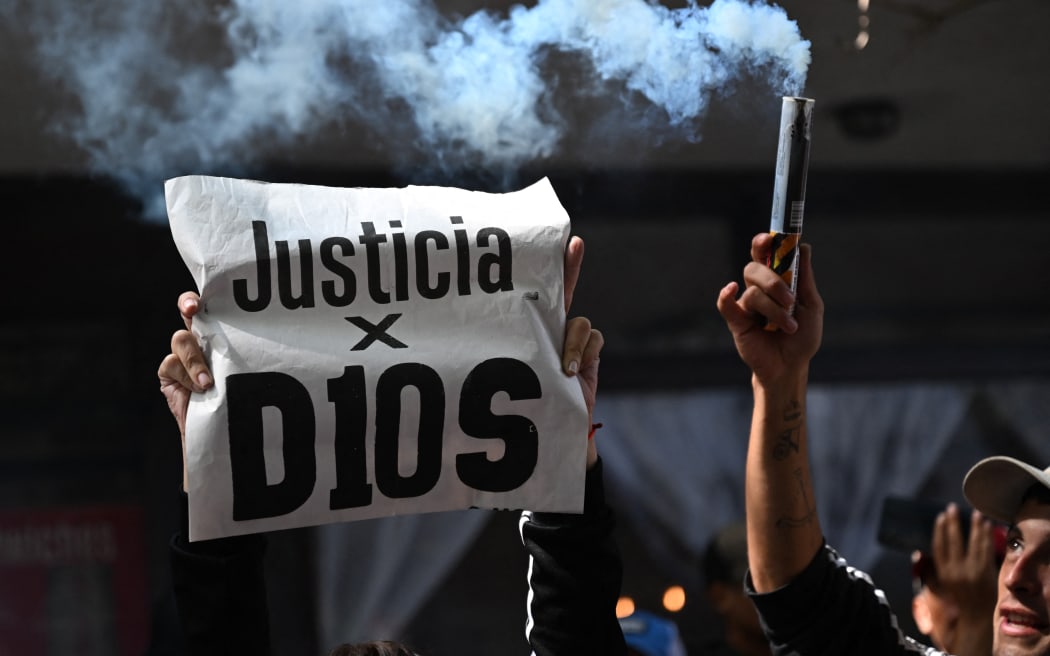 A fan holds a banner that reads in spanish 'Justice for D10s' as he waits outside the San Isidro court during the trial for the death of late Argentine football legend Diego Maradona.