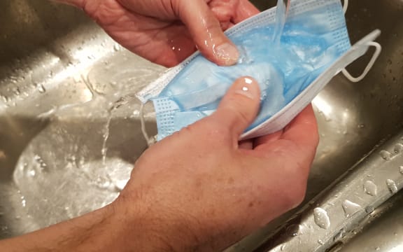 Microbiologist Richard Everts washing a disposable mask in warm water.