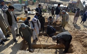 Shiite mourners and relatives dig graves for girls who died in an attack outside a girls' school in Dasht-e-Barchi on the outskirts of Kabul on 9 May, 2021.