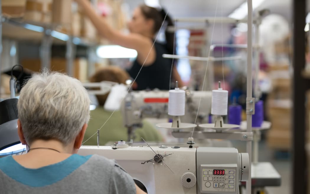 Woman sewing in workshop sitting in rearview