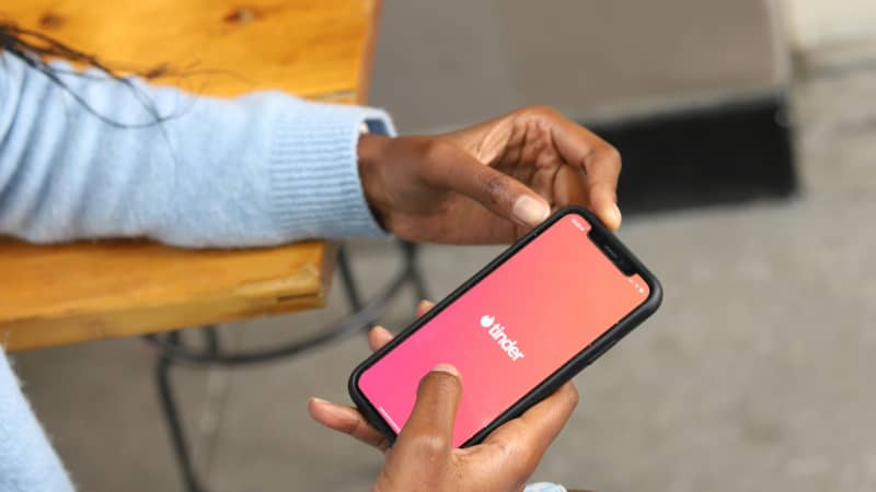 A woman looks at Tinder on her phone