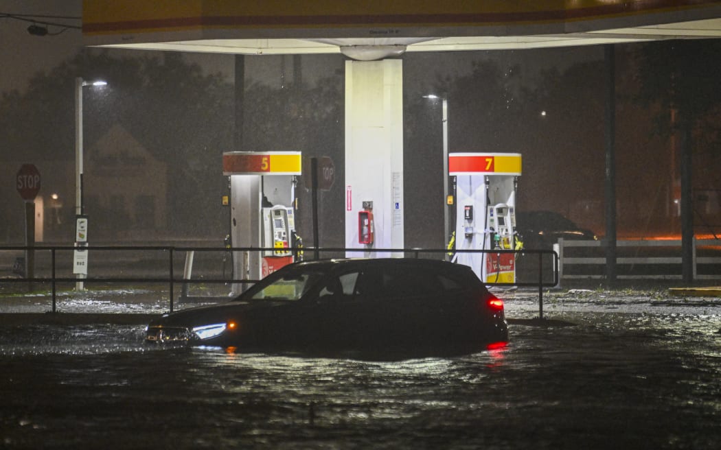 A vehicule is stranded on a water-flooded street after Hurricane Milton made landfall in Brandon, Florida on October 9, 2024. - Milton made landfall in Florida October 9, 2024 as an "extremely dangerous" Category 3 hurricane, packing life-threatening storm surge, extreme winds and flash flooding, the National Hurricane Center (NHC) said. "Data indicate the eye of Hurricane Milton has made landfall near Siesta Key in Sarasota County along the west coast of Florida," the NHC said in an 8:30 pm (0030 GMT Thursday) bulletin. (Photo by Miguel J. Rodriguez Carrillo / AFP)