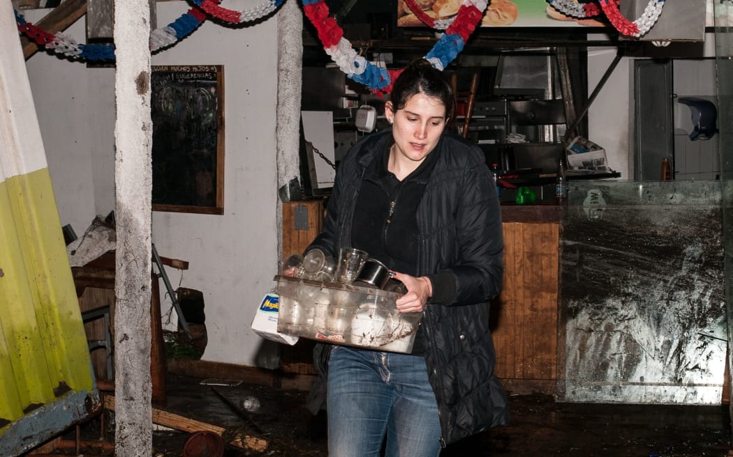 A woman carries belongings out of a store in Concon.
