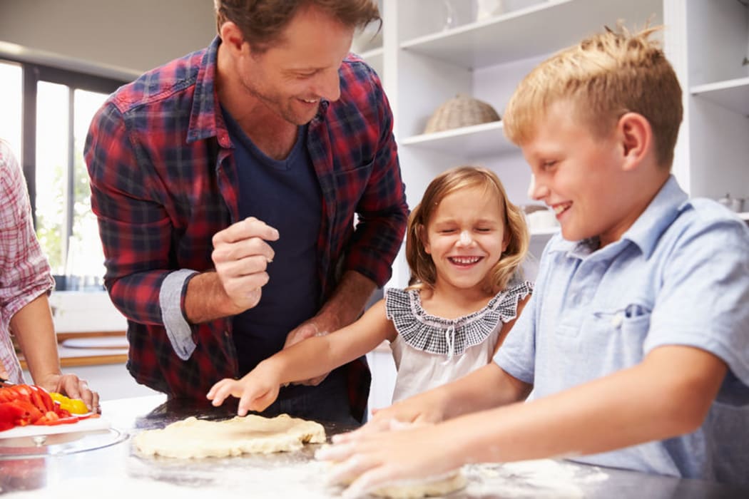 A photo of a father making pizza with kids