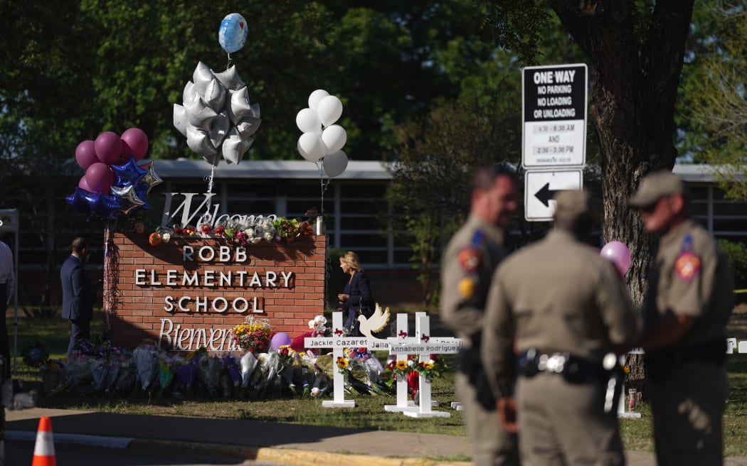 Police stand next to a makeshift memorial outside Robb Elementary School two days after 19 children and two teachers were killed at the elementary school in Uvalde, Texas, on 24 May.