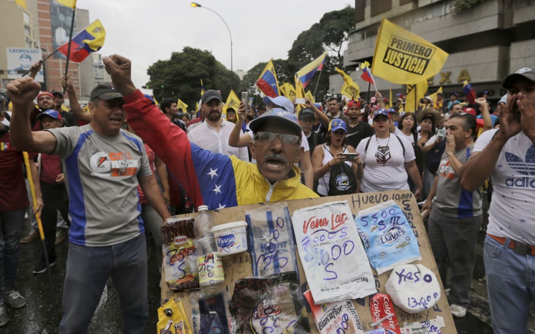 An opposition member holds a poster board with the prices of basic food during a protest against Venezuela's President Nicolas Maduro in Caracas, Venezuela.