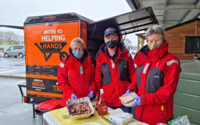 Coastguard volunteers cook bacon for sandwiches at the tradie vaccination and breakfast event.