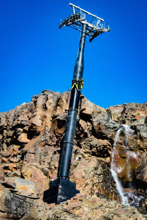A Sky Waka gondola tower dwarfs two workers scaling it.