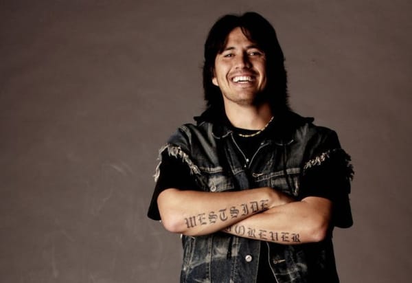 Munter Mason is a young smiling man with long hair and the words 'Westside Forever' tattooed on his crossed arms.