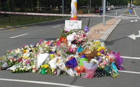People gather near scene of first shooting to lay flowers