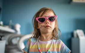 caucasian girl toddler with painted color draws and stains on face