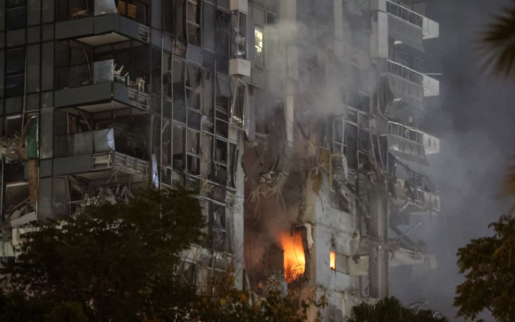 Fire and smoke rise from a building, reportedly hit by a missile fired from Iran, in central Tel Aviv on June 13, 2025. Iran fired a barrage of ballistic missiles at Israel in a counter-strike in the evening on June 13, after an unprecedented onslaught hammered the Islamic republic's top military brass and targeted its nuclear facilities and bases. (Photo by Jack GUEZ / AFP)