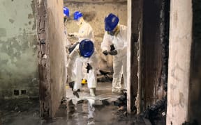 This handout photo released by the Hong Kong Police Force on November 30, 2025 shows officers from the Disaster Victims Identification Unit (DVIU) working inside an apartment block in the aftermath of a fire at the Wang Fuk Court residential estate in Hong Kong's Tai Po district. The death toll in a fire that tore through a Hong Kong residential estate this week has risen to 146, police said on November 30. (Photo by Handout / HONG KONG POLICE FORCE / AFP) / RESTRICTED TO EDITORIAL USE - MANDATORY CREDIT "AFP PHOTO /  HONG KONG POLICE FORCE" - HANDOUT - NO MARKETING NO ADVERTISING CAMPAIGNS - DISTRIBUTED AS A SERVICE TO CLIENTS