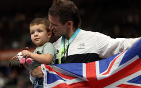 Gold medallist Aaron Gate holds son Axel as he celebrates during the medal presentation ceremony for the men's 1000m time trial cycling event at the Commonwealth Games on 1 August 2022.