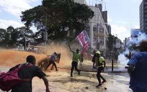 Protesters scatter as Kenya police spray water canon at them during a protest over proposed tax hikes in a finance bill in downtown Nairobi, Kenya Tuesday, June. 25, 2024. (AP Photo/Brian Inganga)