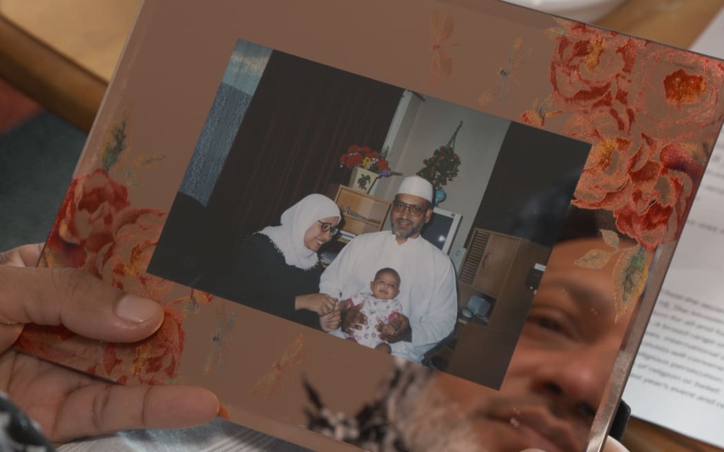 Farid Ahmed holding an old photo of him with his wife Husna, who died in the 15 March shootings, and his daughter.