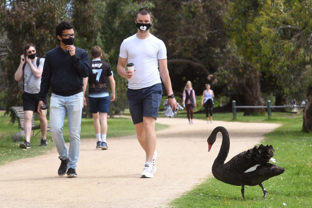 People walk past a swan around Melbourne's Albert Park Lake, 12 October 2020.