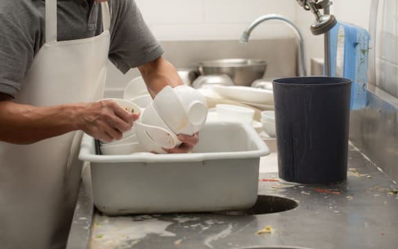 Man washing dish on sink at restaurant
