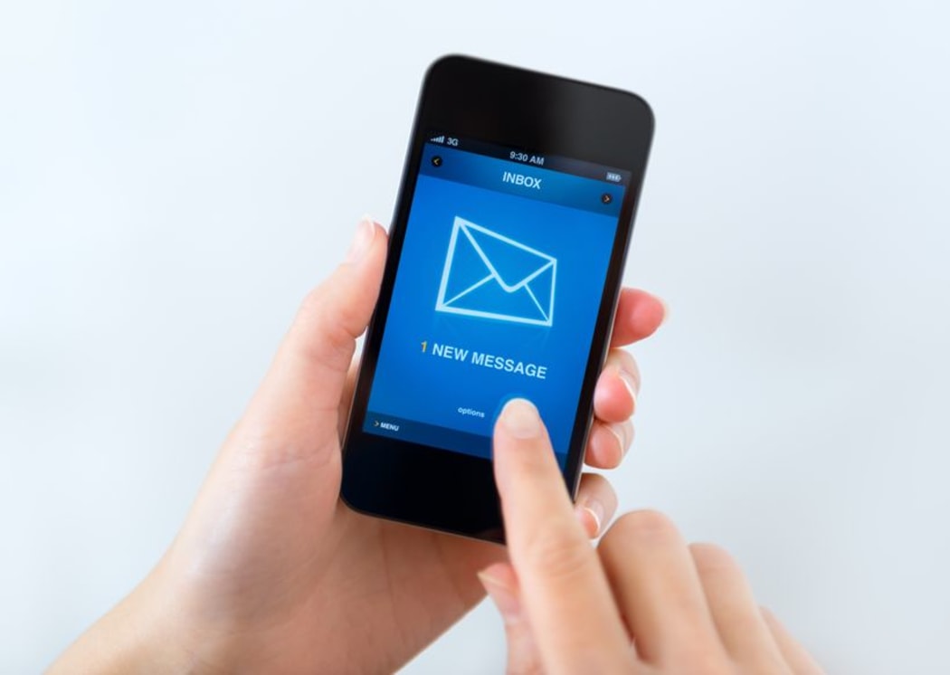 Woman holding phone showing email inbox.