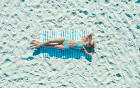 Woman tanning on the beach in swimsuit.