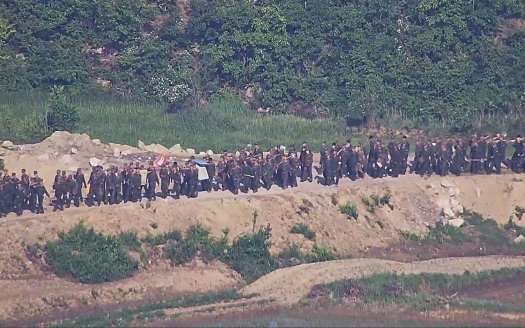 In this undated photo provided on Tuesday, June 18, 2024, by South Korea Defense Ministry, North Korean soldiers work at an undisclosed location near the border area, as seen from a South Korean guard area. South Korean soldiers fired warning shots to repel North Korean soldiers who temporarily crossed the rivals' land border Tuesday for the second time this month, South Korea's military said. (South Korea Defense Ministry via AP)