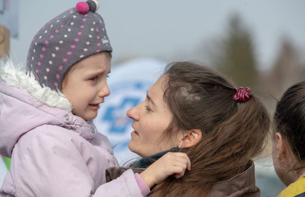 A group of people fleeing Ukraine stand in a line after arriving at the border crossing in Medyka, Poland, on Tuesday, March 15, 2022.