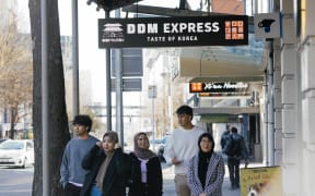 People passing by Asian restaurants on Hobson street in Auckland CBD, July 2024.