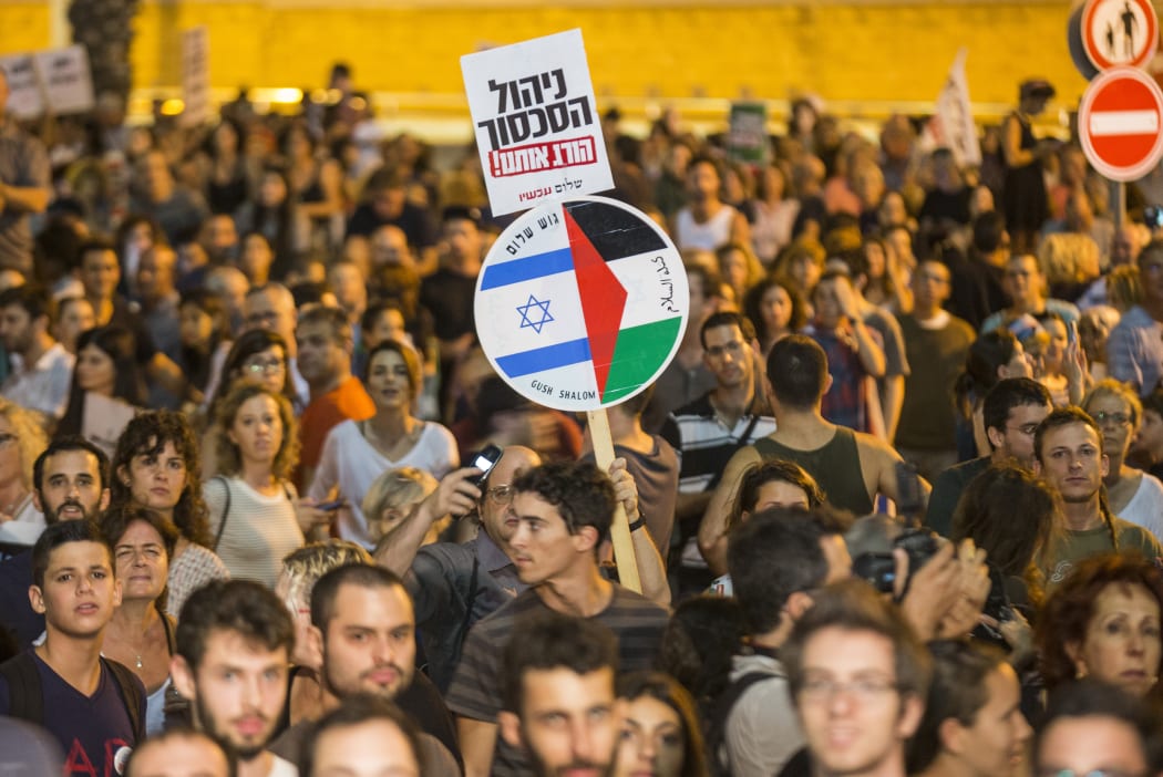 An Israeli left-wing activist holds a banner bearing images of the Israeli and Palestinian flags during a rally demanding fresh Israeli-Palestinian peace talks