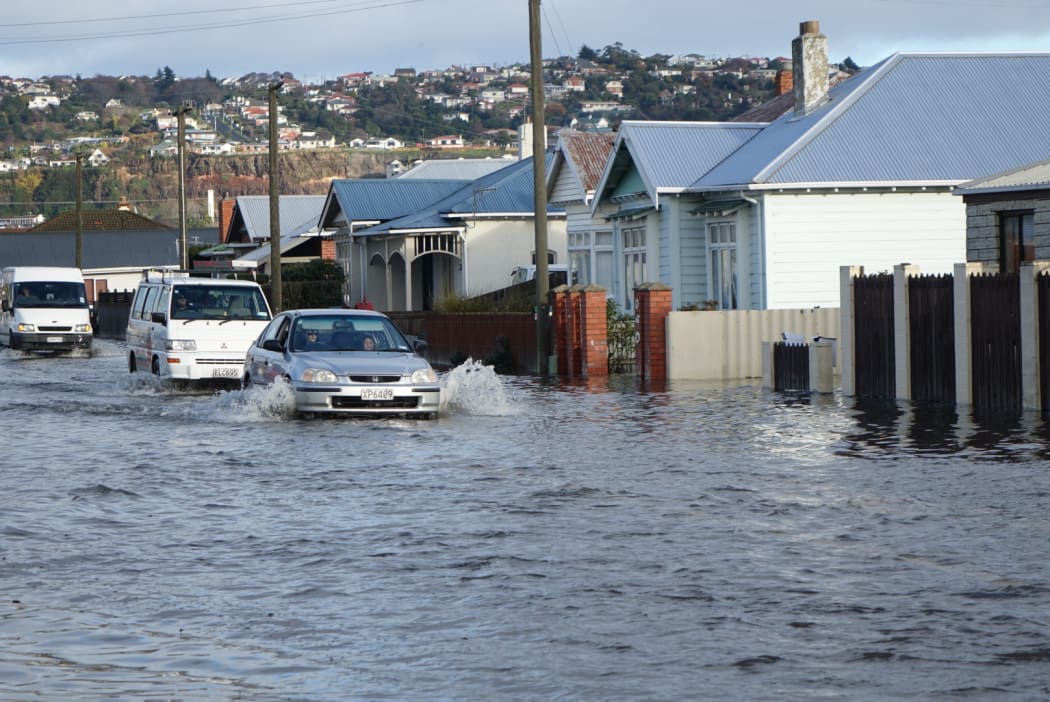 A car powers through floodwaters in south Dunedin on Thursday.