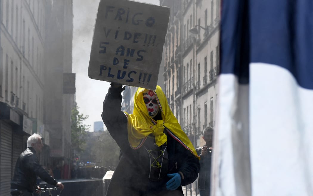 A demonstrator holds a sign reading " Empty fridge, five years more" during the annual May Day rally in Paris, 1 May, 2022.