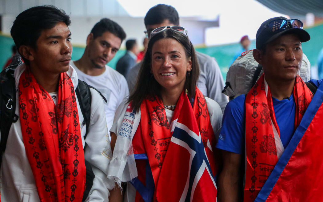 Norwegian climber Kristin Harila (C) and Tenjen Sherpa (L), who set the record for the fastest summit of all 14 of the world's 8,000-metre peaks, along with the youngest K2 summiteer, Nima Rinji Sherpa (R), arrive at Tribhuvan International Airport in Kathmandu on 5 August, 2023.
