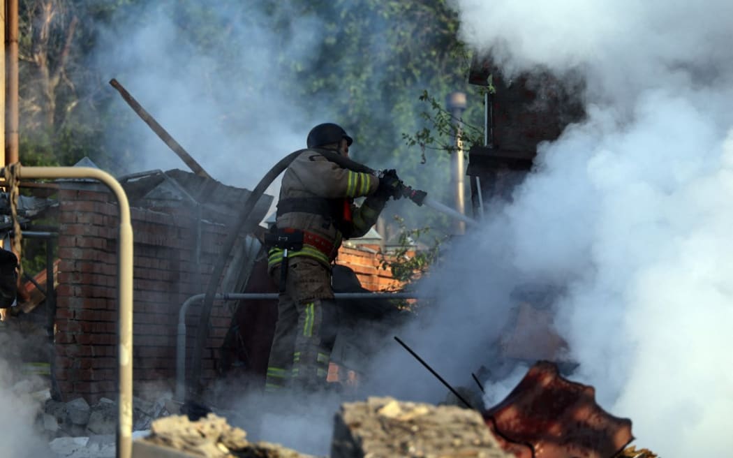 A firefighter is suppressing a fire caused by a Russian missile attack in Kharkiv, northeastern Ukraine, on May 10, 2024. On the night of May 10, Russian forces attacked Kharkiv with an S-300 missile, injuring an 11-year-old child and a 72-year-old woman in the private sector. Three houses are on fire, with two destroyed and one damaged. In total, 26 buildings have been destroyed, and more than 300 windows have been smashed. NO USE RUSSIA. NO USE BELARUS. (Photo by Ukrinform/NurPhoto) (Photo by Vyacheslav Madiyevskyy / NurPhoto / NurPhoto via AFP)