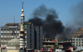Smoke billows during clashes in the predominantly Druze city of Sweida on July 15, 2025, following clashes between Bedouin tribes and Druze fighters. Syrian government forces entered the majority Druze city of Sweida on July 15, 2025, the interior ministry said, aiming to end clashes with Bedouin tribes that have killed nearly 100 people. (Photo by Shadi AL-DUBAISI / AFP)