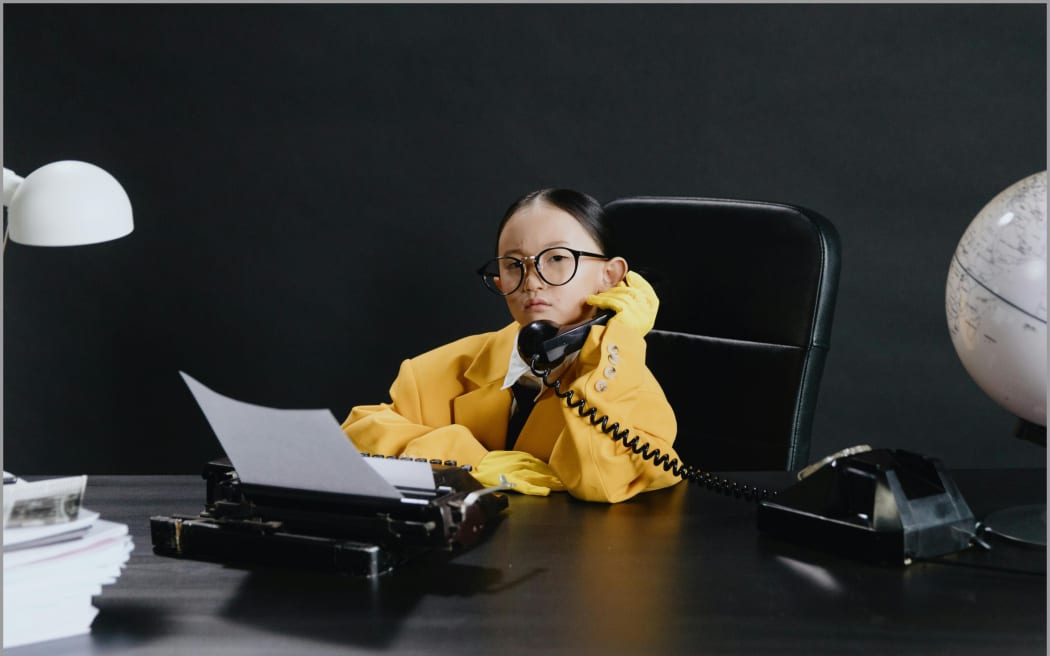 Image of young girl sitting at desk on phone.