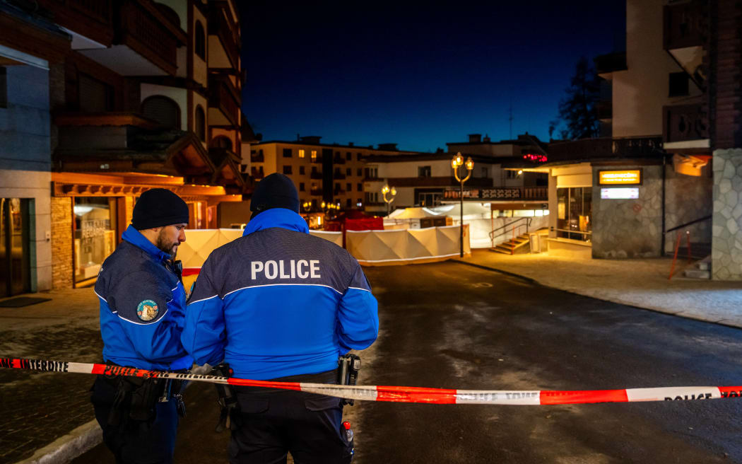 Police control access to the street where a fire ripped through a crowded bar during New Year's Eve celebrations in the Alpine ski resort town of Crans-Montana on January 1, 2026. Several dozen people are presumed dead and around 100 injured after a fire ripped through a crowded bar in the luxury Swiss ski resort of Crans-Montana, Swiss police said on January 1, 2026. Police, firefighters and rescuers rushed to the popular resort, which is set to host the Ski World Cup from January 30, after the fire broke out in the early hours of New Year's Day. (Photo by MAXIME SCHMID / AFP)