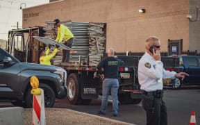 Workers unload fencing from a truck at the Maricopa County Election and Tabulation Center in Phoenix, Arizona, on November 4, 2024. - Concrete barriers, high wire fences and armed agents inside: on the eve of the American presidential election, the election center in Phoenix, Arizona, looks like a fortress. (Photo by Olivier Touron / AFP)