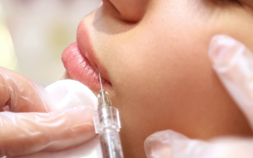 A woman receives a dermal filler injection to the lips
